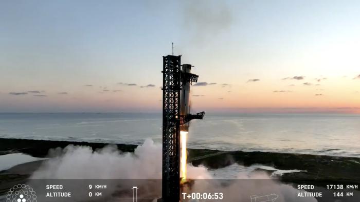 SpaceX's Super Heavy booster is pictured as it is caught by the mechanical arms of the launch tower at the company's Texas launch site