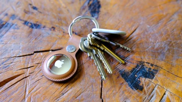 An AirTag in a leather keychain case attached to a ring with several keys