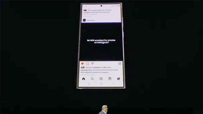 A Samsung Galaxy S24 displays an Instagram feed entry stating it's the "...first HDR enabled for photos on Instagram" on a large screen above a presenter's head at Samsung's Unpacked 2024 event.