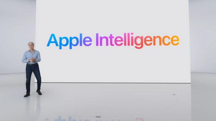 Apple software lead Craig Federighi standing in front of a large white wall with the colorful words "Apple Intelligence."