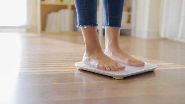 woman weighing on scale to measure her weight