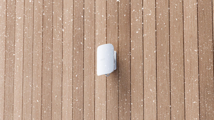 Image of the Eero Outdoor 7 on a wood wall while snow falls.